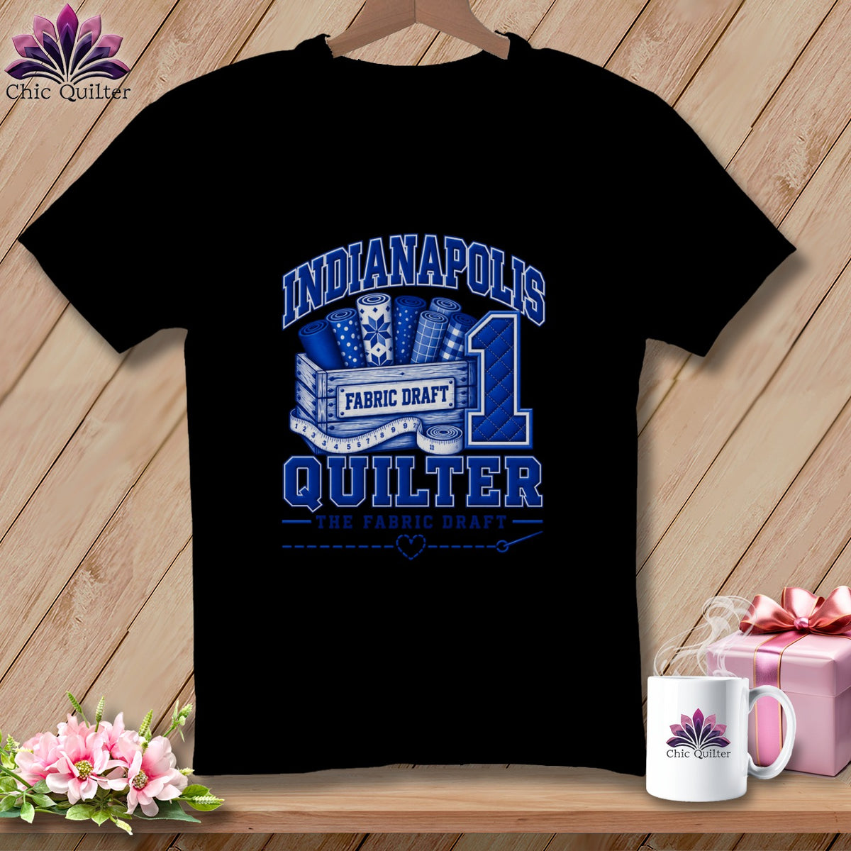 A black t-shirt with a blue graphic reading Indianapolis Quilter, featuring fabric bolts and a measuring tape.