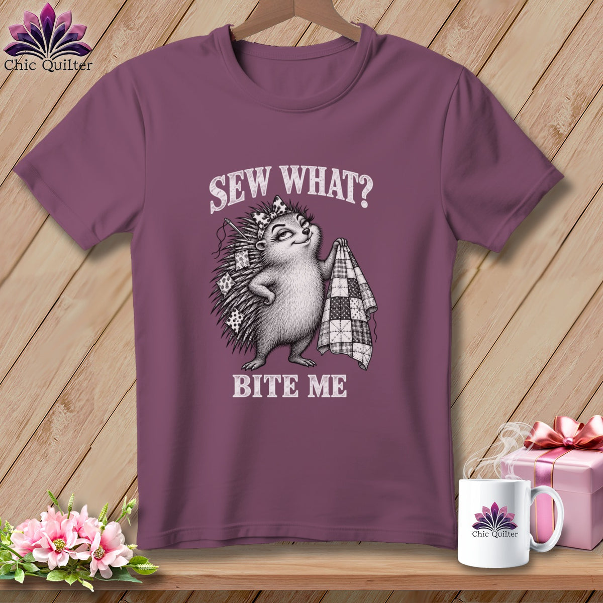 Mauve t-shirt hanging on a wooden background, featuring a hedgehog graphic with the text Sew What? Bite Me.