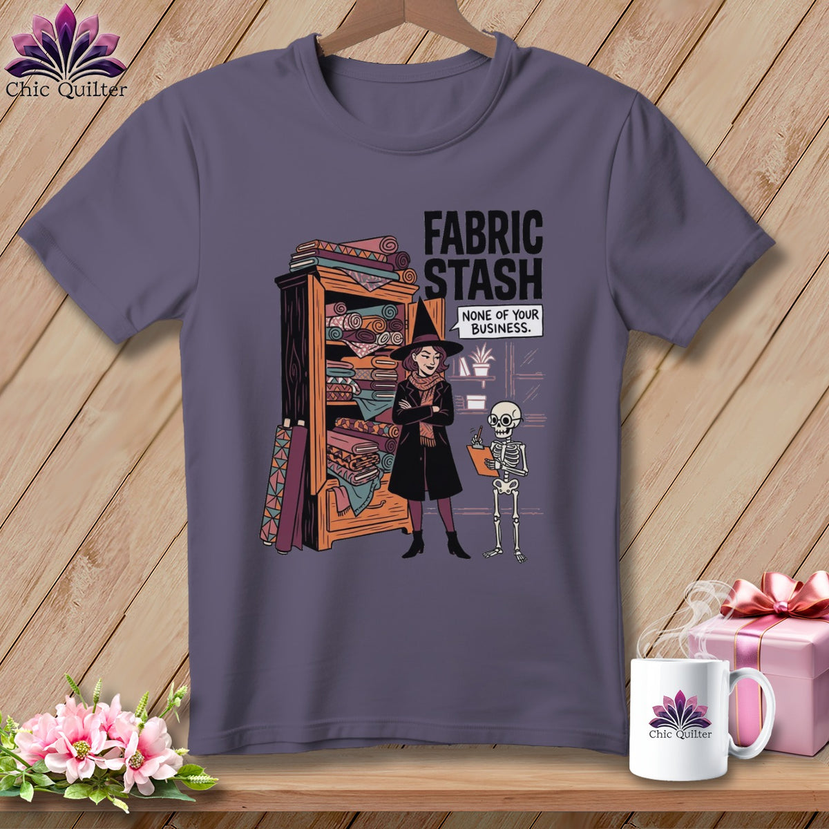 T-shirt graphic of a witch by a fabric stash with text: "FABRIC STASH NONE OF YOUR BUSINESS."
