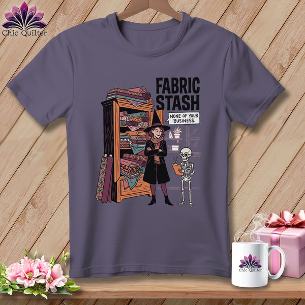 T-shirt graphic of a witch by a fabric stash with text: "FABRIC STASH NONE OF YOUR BUSINESS."