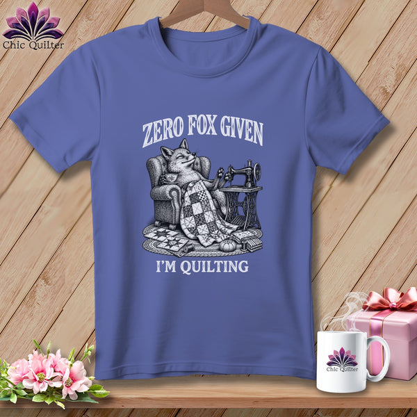 T-shirt with a fox sitting in a chair with a quilt, sewing machine, and text "Zero Fox Given I'm Quilting".