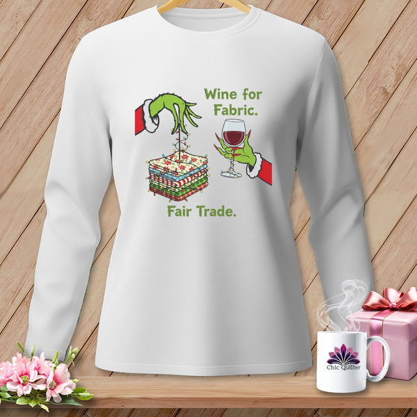White sweatshirt with Grinch-like hands holding fabric, a glass of wine, and text "Wine for Fabric. Fair Trade."