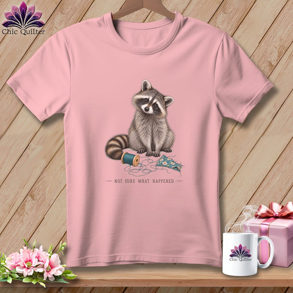 Pink t-shirt with raccoon, spool of thread, fabric, and text "NOT SURE WHAT HAPPENED".
