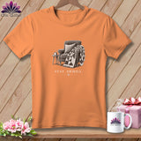 Orange t-shirt with a graphic of an armchair, quilt, side table, and the text 