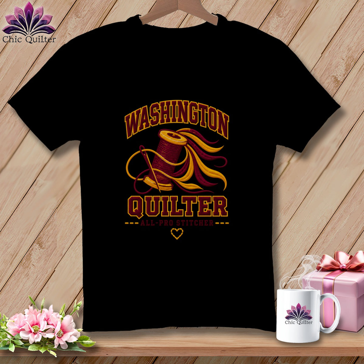 Black t-shirt featuring a spool of thread graphic, the text Washington Quilter, and a needle on a wooden background.