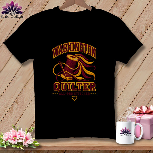 Black t-shirt featuring a spool of thread graphic, the text Washington Quilter, and a needle on a wooden background.