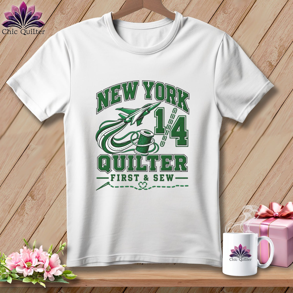 A white t-shirt hanging on a wooden background, featuring green text reading "New York Quilter" with airplane and spool graphics.