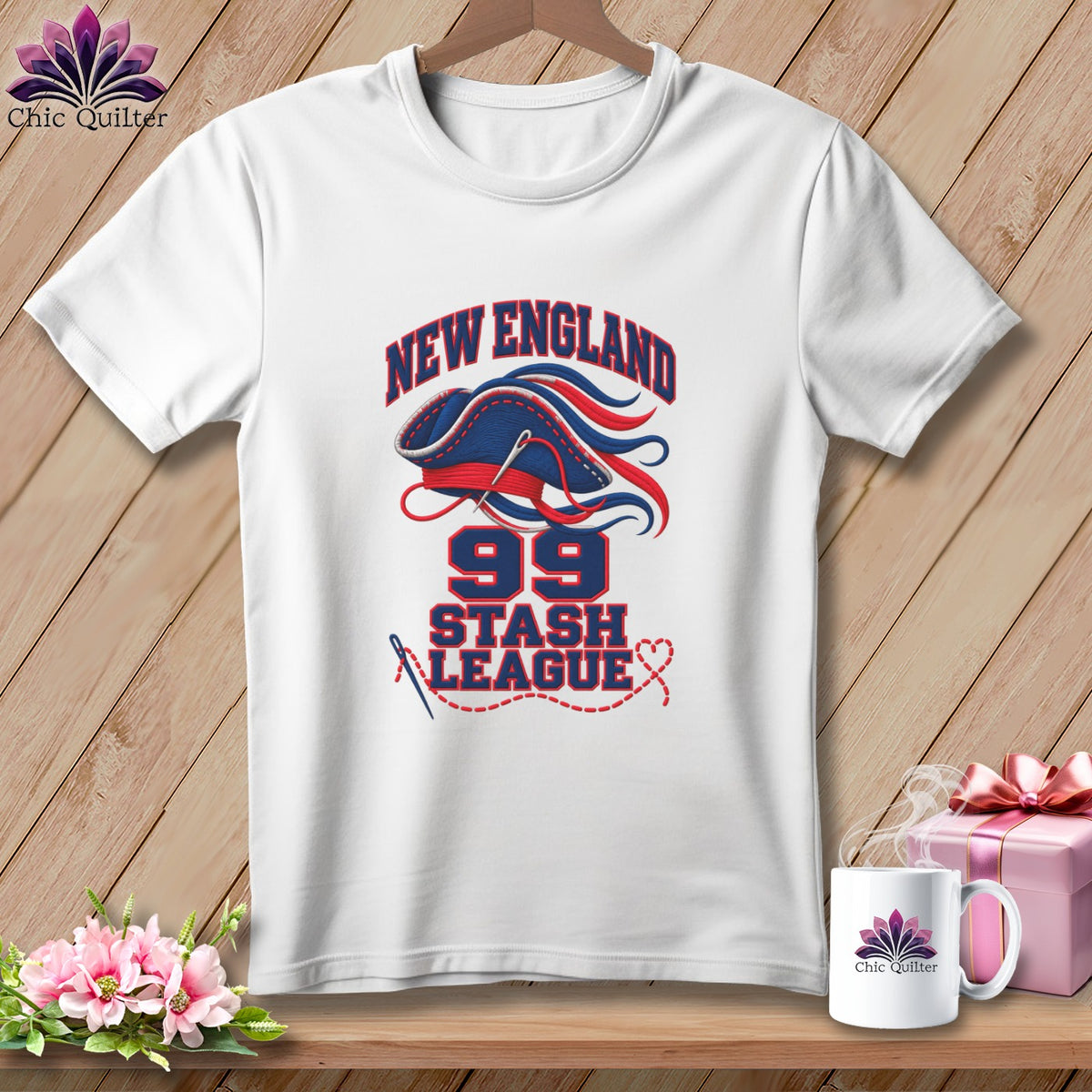 A white t-shirt on a wooden background features New England 99 Stash League graphics in red and blue.