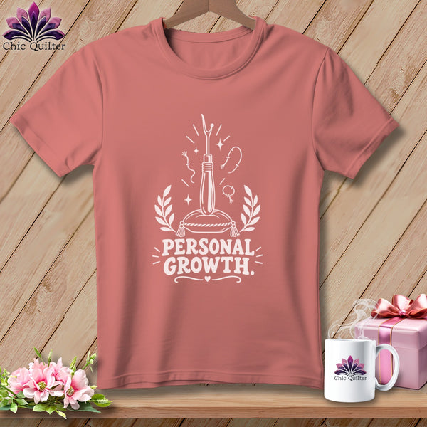 Rose-colored t-shirt with "Personal Growth" and sewing graphics.