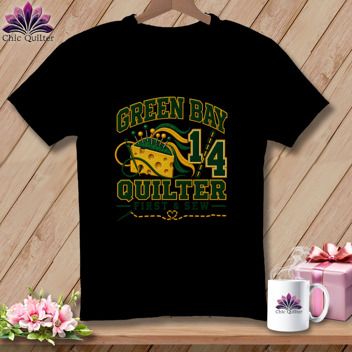 A black t-shirt hangs on a wooden hanger featuring Green Bay Quilter text and sewing-themed cheese graphic.