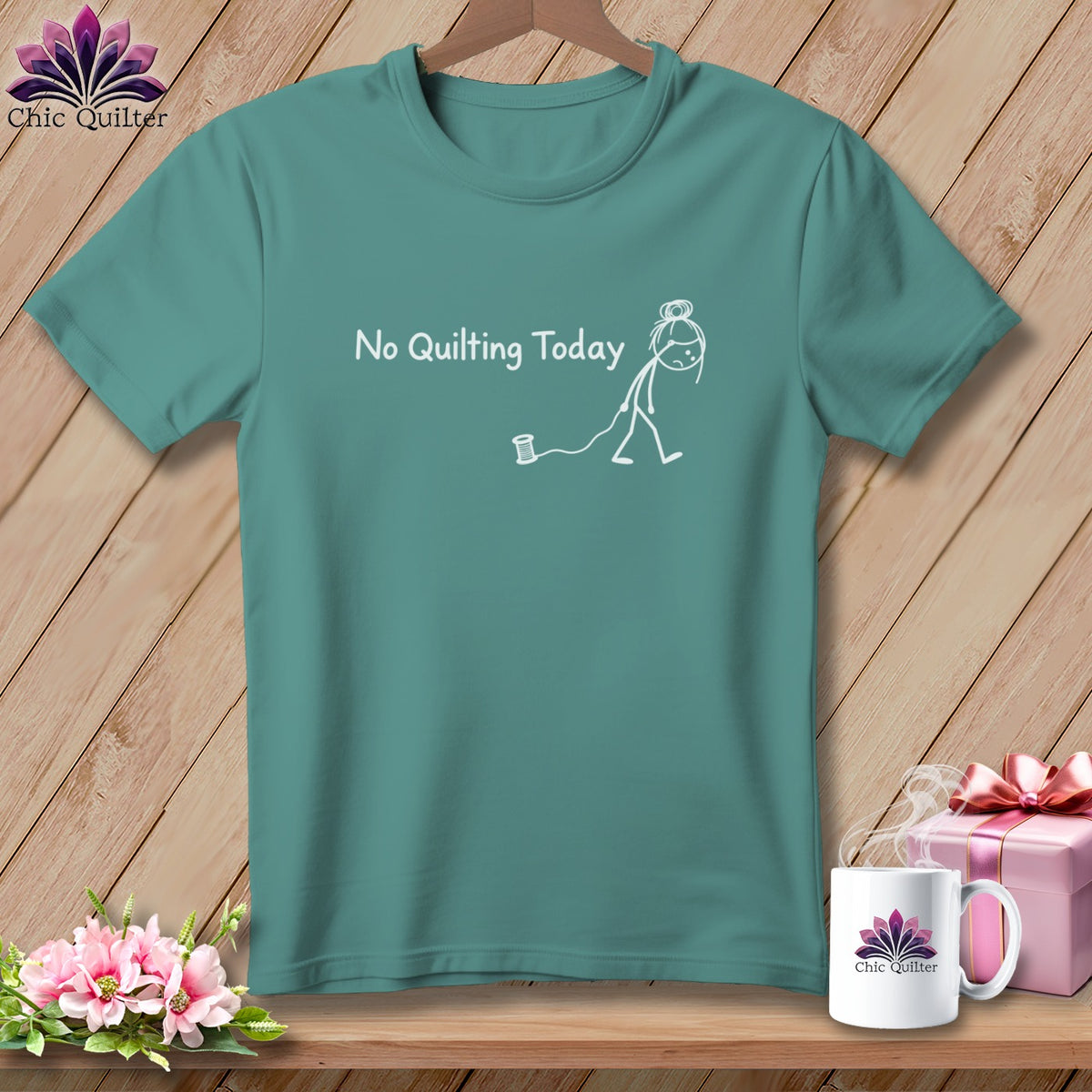 Teal t-shirt with "No Quilting Today" and a stick figure pulling a thread spool.