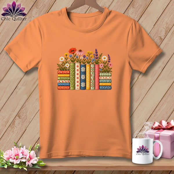 Orange crewneck t-shirt featuring a graphic of colorful stacked books and flowers on a wooden background.
