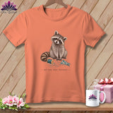 T-shirt with raccoon, spool of thread, fabric, and text 