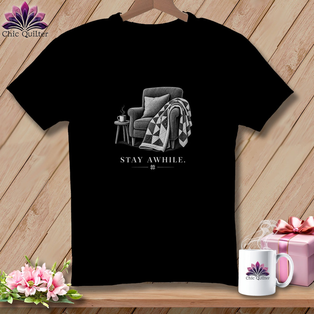 Black t-shirt with illustration of armchair, blanket, and coffee cup. Text reads "STAY AWHILE."