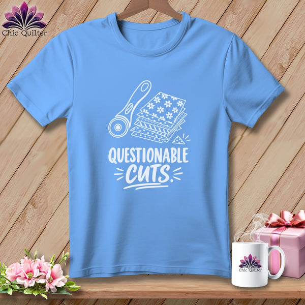 Light blue t-shirt with white graphic of rotary cutter and fabric stacks, text reads "Questionable Cuts".
