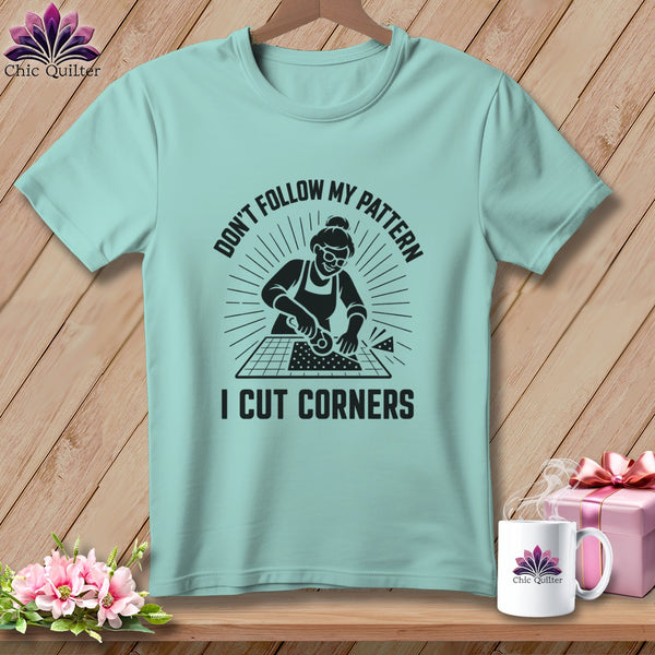 Light teal t-shirt with graphic of woman cutting fabric and text "DON'T FOLLOW MY PATTERN I CUT CORNERS".