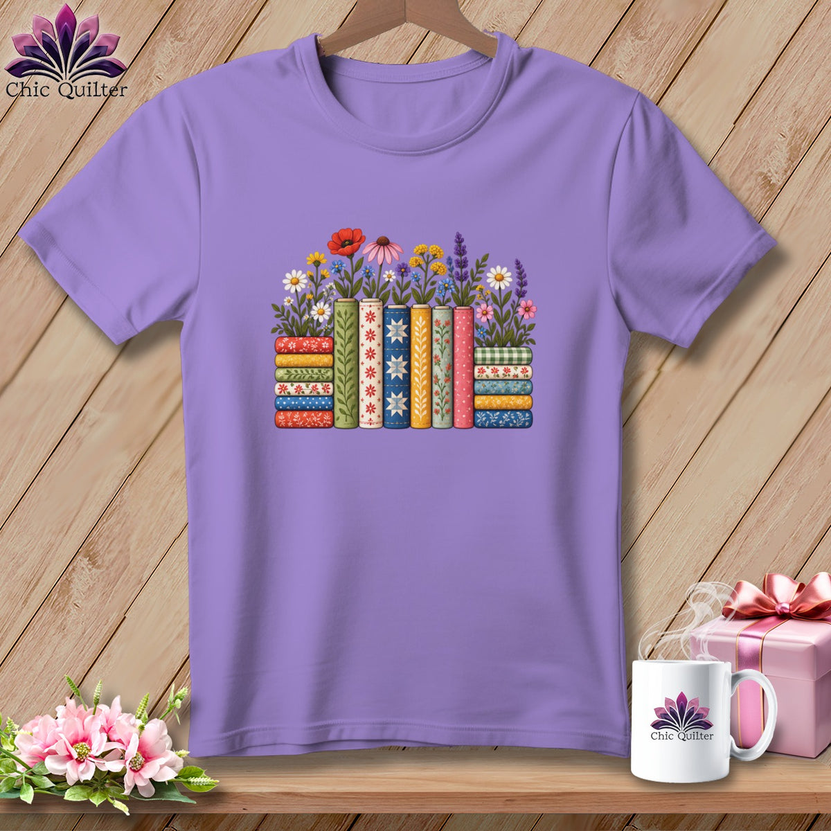 A purple short-sleeved t-shirt features a graphic of colorful stacked quilt bolts topped with flowers.