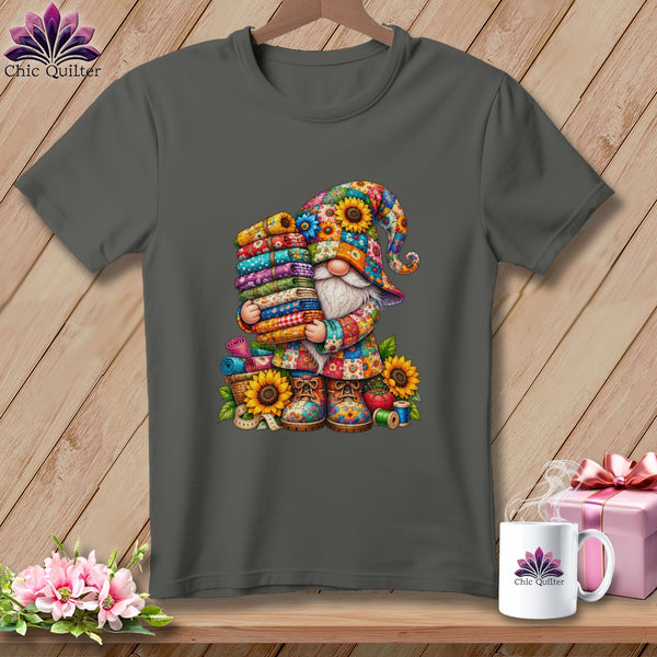Charcoal gray t-shirt featuring a colorful gnome holding a stack of patterned fabrics and sewing supplies.