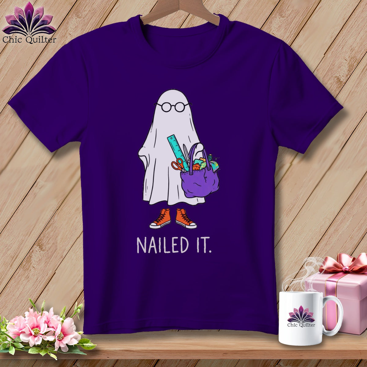 Ghost with glasses and sewing supplies, "NAILED IT." text, on purple shirt.