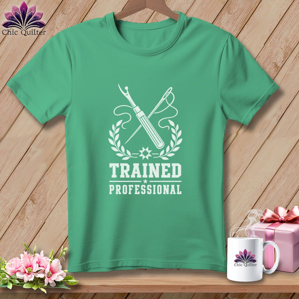 Green t-shirt with white graphic of sewing tools and text "TRAINED PROFESSIONAL".