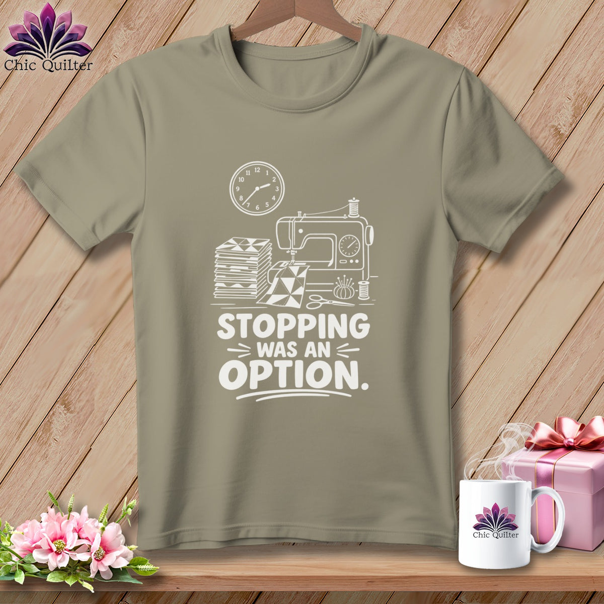 Khaki t-shirt with white graphic of sewing machine, fabric, and text "Stopping Was An Option."