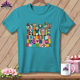 A turquoise t-shirt displays a graphic of cartoon farm animals peeking over a colorful patchwork quilt.