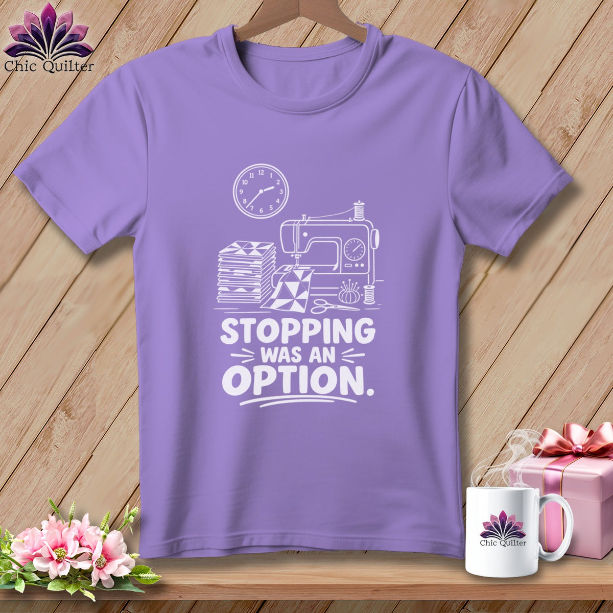 Purple t-shirt with white line art of sewing machine, fabric stacks, clock, and scissors. Text reads "STOPPING WAS AN OPTION."