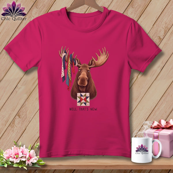Pink t-shirt with a moose wearing fabric strips on antlers and a quilt block.