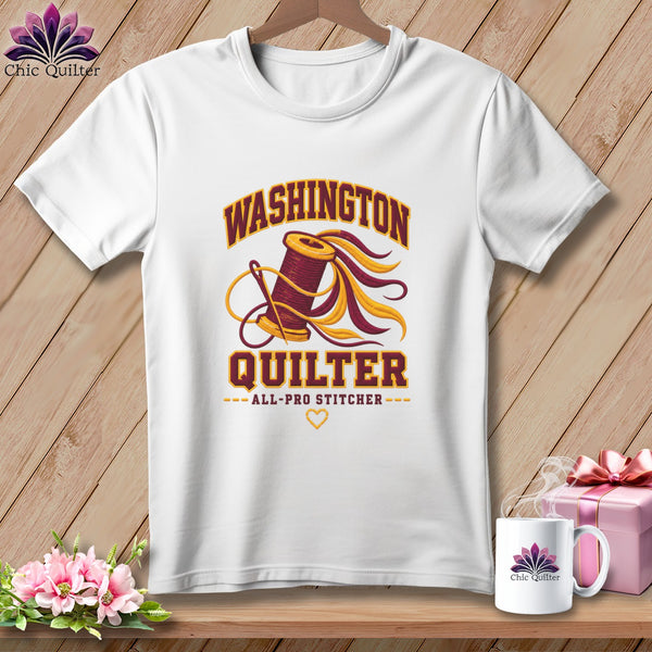 A white t-shirt featuring a quilting graphic and the text "Washington Quilter All-Pro Stitcher".