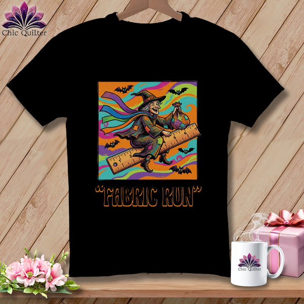 Black t-shirt with a cartoon witch riding a ruler, holding a fabric bag, with bats.