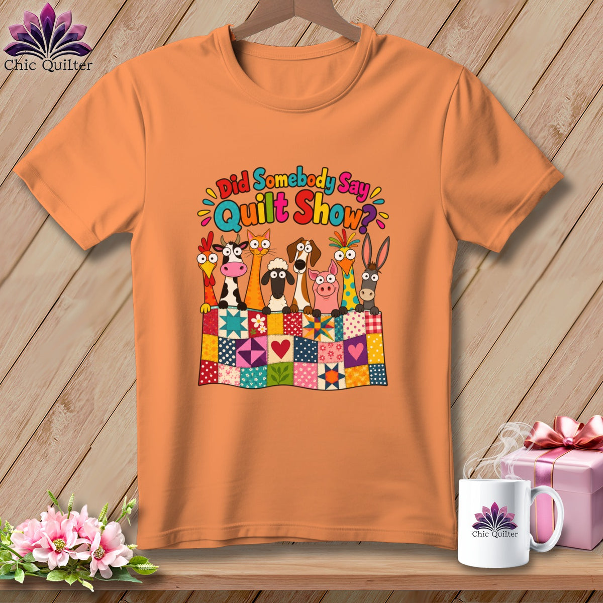 An orange t-shirt displays a graphic of cartoon farm animals behind a colorful quilt, with the text Did Somebody Say Quilt Show.