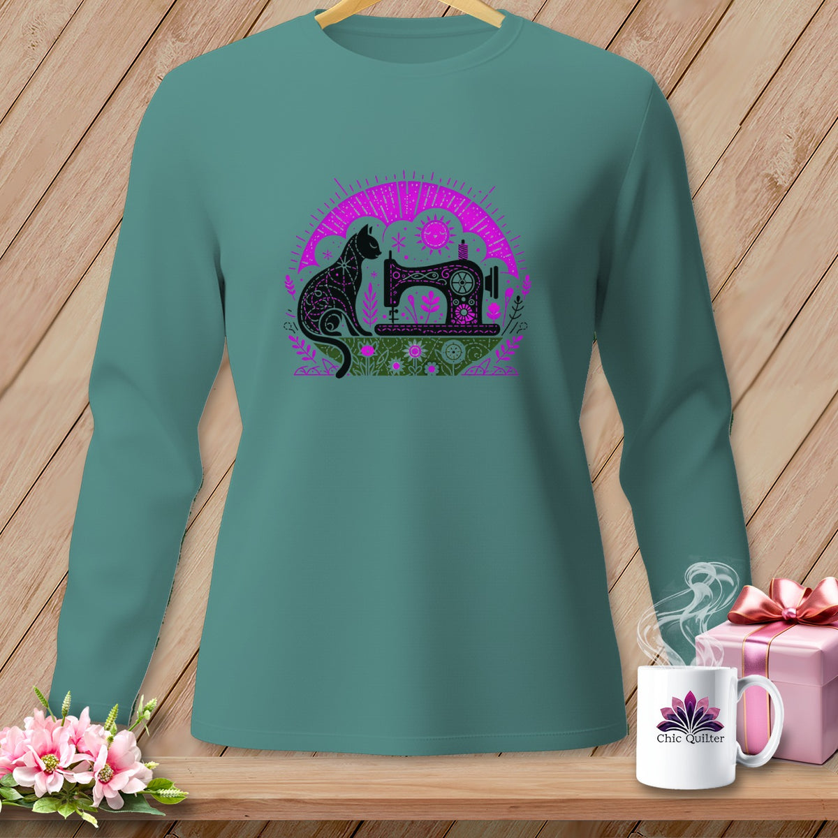 Teal long-sleeve shirt with a black and pink cat and sewing machine graphic.