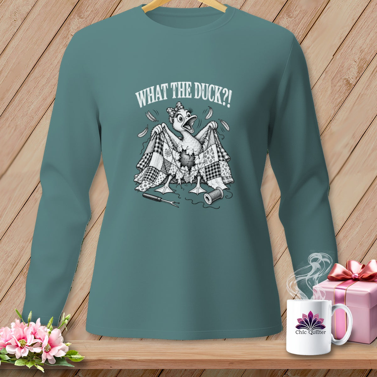 Teal long-sleeved shirt with a graphic of a panicked duck holding a torn quilt.