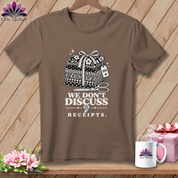Brown t-shirt with stack of fabrics, scissors, and text "WE DON'T DISCUSS RECEIPTS."