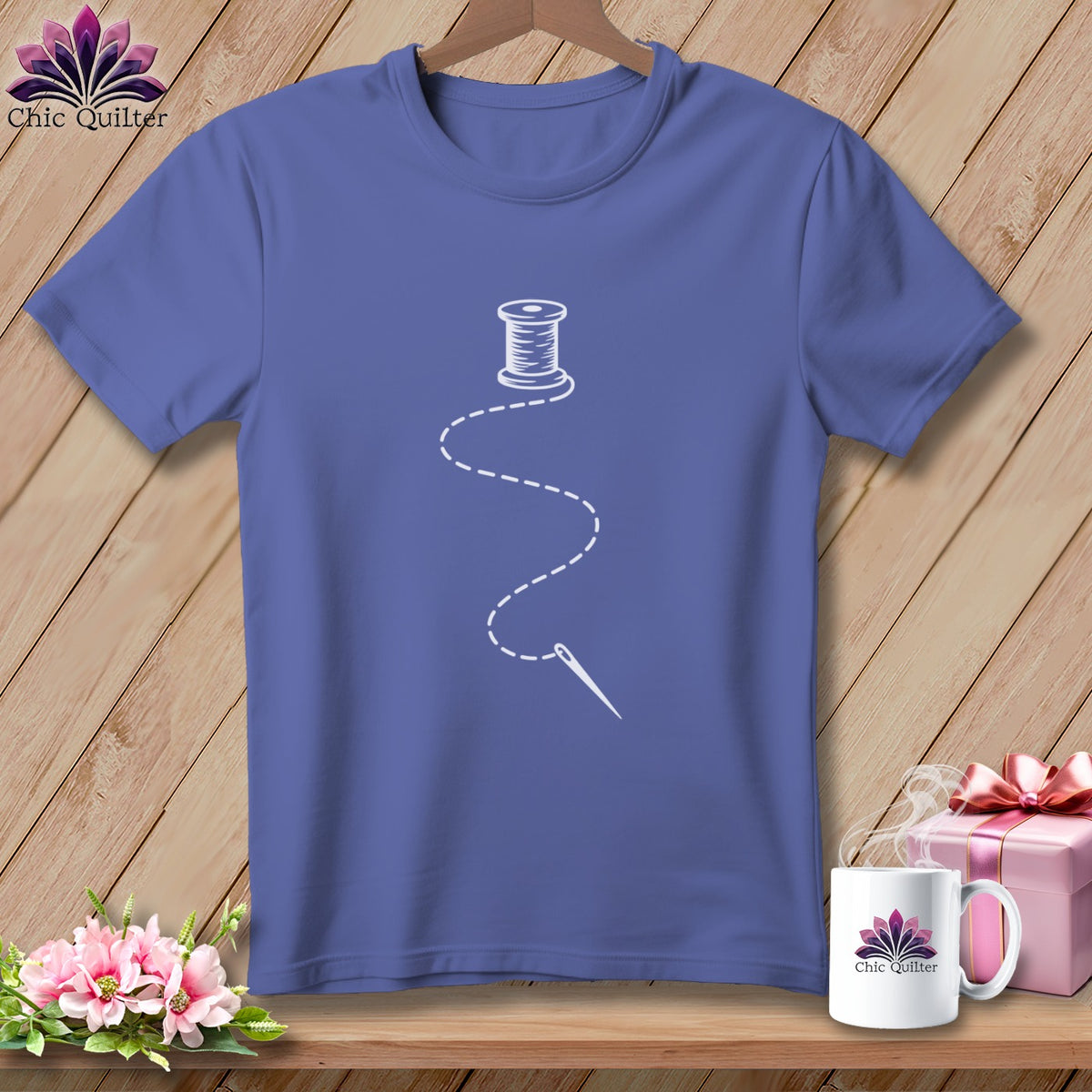 Purple t-shirt with white spool of thread and needle graphic.