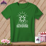 Green t-shirt with a white graphic of a quilt square, sun, and sewing needle, and text 