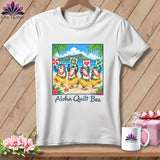 A white t-shirt hanging against a wooden wall features a graphic of four hula-dancing penguins on a beach, with the text Aloha Quilt Bee underneath.