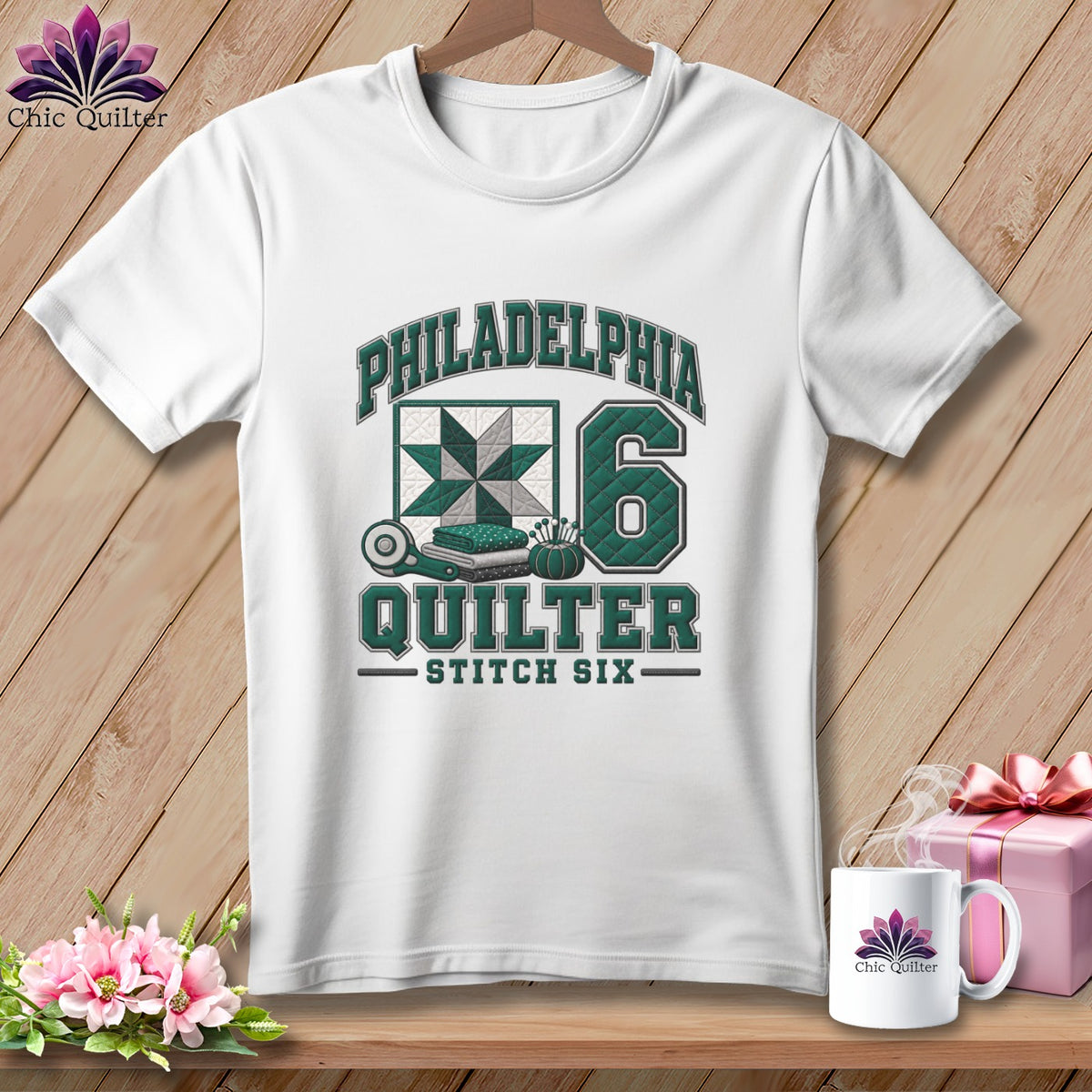 A white t-shirt features green lettering that reads Philadelphia Quilter Stitch Six alongside a quilt block graphic and the number 6.