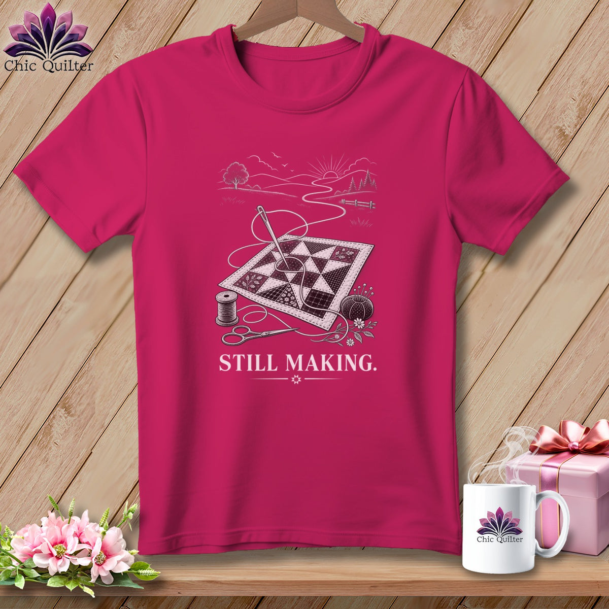Pink t-shirt with a line drawing of a quilt, needle, thread, scissors, and text "STILL MAKING."