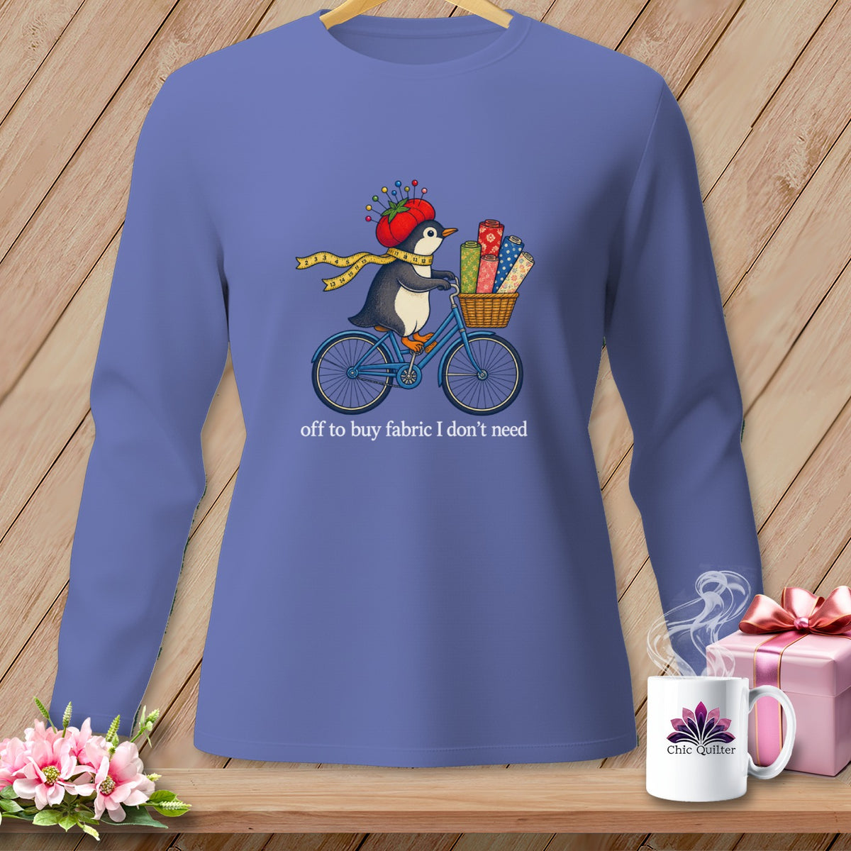 Penguin riding a bike with fabric rolls, text "off to buy fabric I don't need".