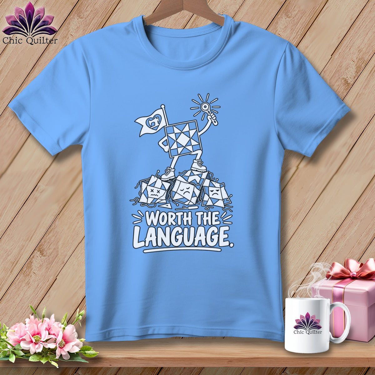 Blue t-shirt graphic with a quilt block character standing on defeated blocks and text "WORTH THE LANGUAGE."