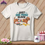 White t-shirt with dachshund, quilt square, fabric stacks, rotary cutter, and measuring tape.