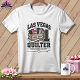 A white crewneck t-shirt featuring a quilting graphic with Las Vegas Quilter text, hanging on a wooden background.