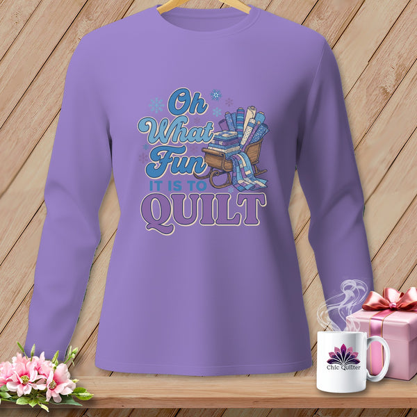 Purple long-sleeve shirt with "Oh What Fun It Is To Quilt" graphic and sled of fabric.