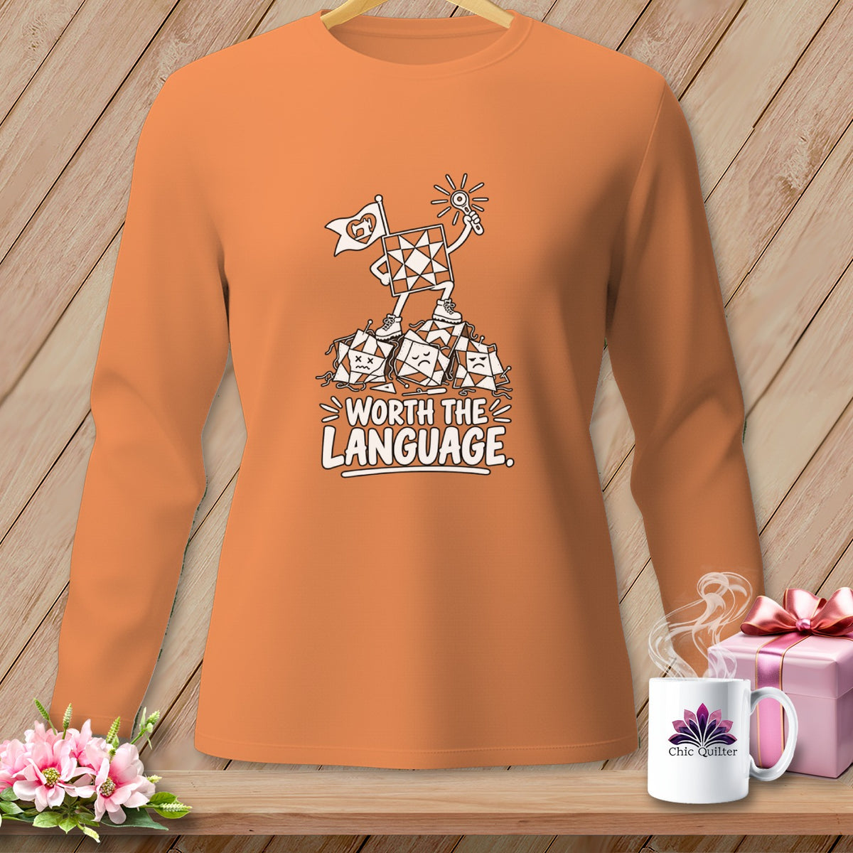 Orange long-sleeve shirt with a quilt square character and "Worth The Language" text.