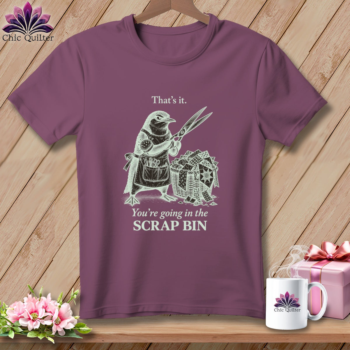 T-shirt graphic with a bird holding scissors over a scrap quilt basket, text reads "That's it. You're going in the SCRAP BIN."