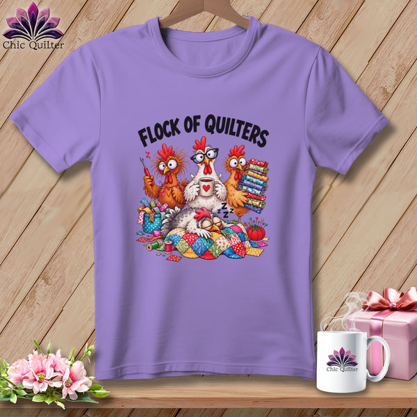 A light purple t-shirt featuring a cartoon graphic of four chickens and the text "FLOCK OF QUILTERS".