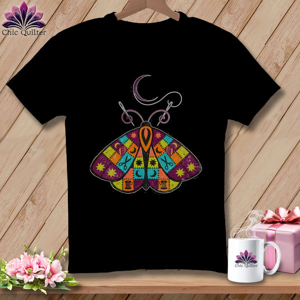 Black t-shirt with a colorful patchwork moth design and sewing elements.