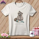 T-shirt graphic featuring a raccoon with sewing supplies and the text 