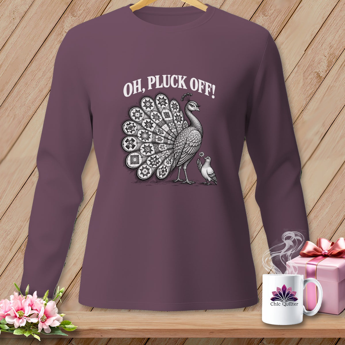 A plum-colored long-sleeve shirt displays a vintage-style peacock graphic with the text Oh Pluck Off above it.